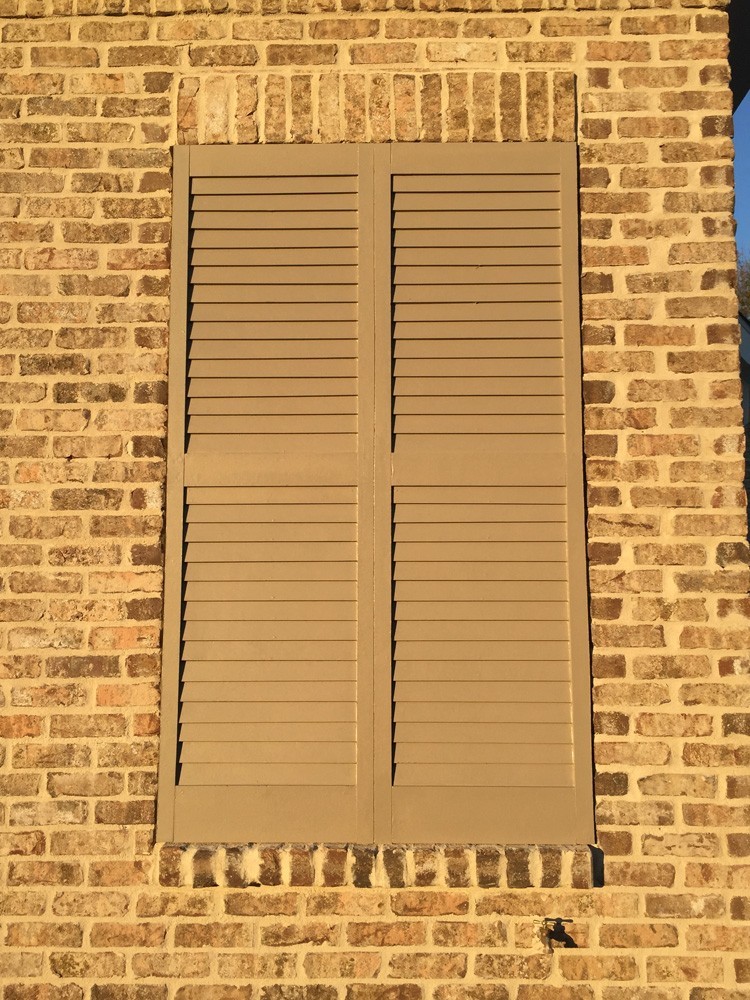 Tan shutters on brown brick in direct sunlight - Strong Shield
